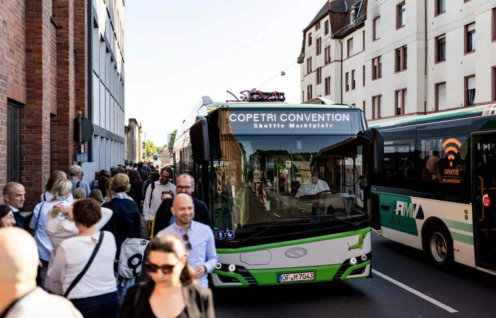 Anreise zur COPETRI Convention Bild mit Bus und menschen die aussteigen und zur Convention laufen